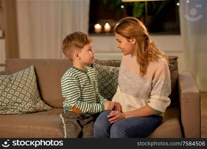 family, love and people concept - happy smiling mother talking to her little son in evening. happy smiling mother talking to her son at home