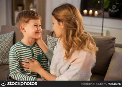 family, love and people concept - happy smiling mother talking to her little son in evening. happy smiling mother talking to her son at home