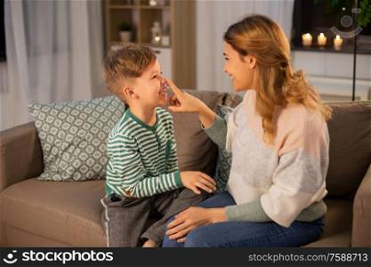 family, love and people concept - happy smiling mother touching her little son&rsquo;s nose at home in evening. happy mother touching little son&rsquo;s nose at home