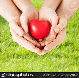 family, love and relationships concept - closeup of woman and man hands with heart