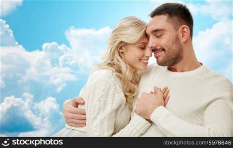 family, love, happiness, affection and people concept - happy couple cuddling over blue sky and clouds background