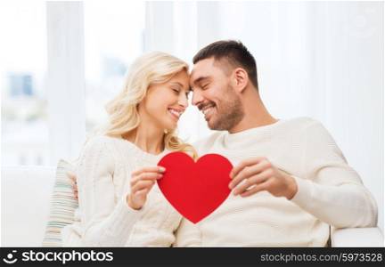 family, love, valentines day and people concept - happy couple with red heart hugging on sofa at home
