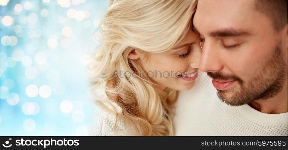 family, love, winter and people concept - close up of happy couple faces with closed eyes over blue holidays lights background