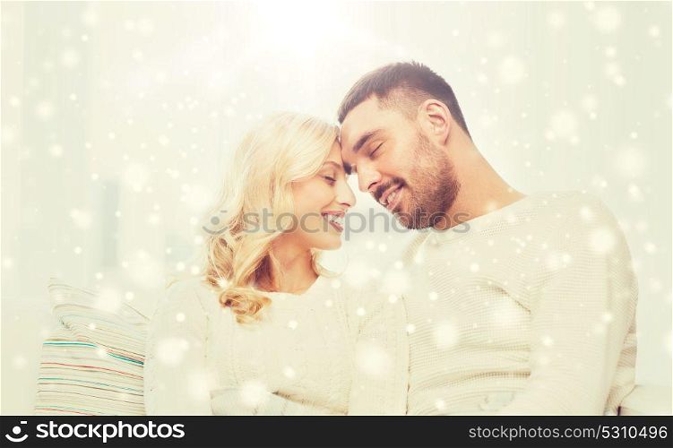 family, love, winter, holidays and people concept - happy couple covered with plaid sitting on sofa at home. happy couple covered with plaid on sofa at home