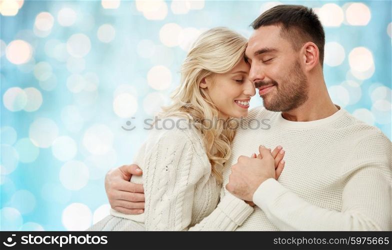 family, love, winter, holidays and people concept - happy couple over blue holidays lights background