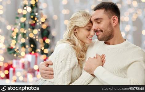 family, love, winter, holidays and people concept - happy couple over christmas tree lights background
