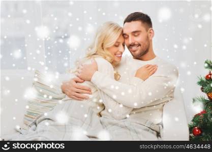 family, love, winter holidays, christmas and people concept - happy couple hugging on sofa at home