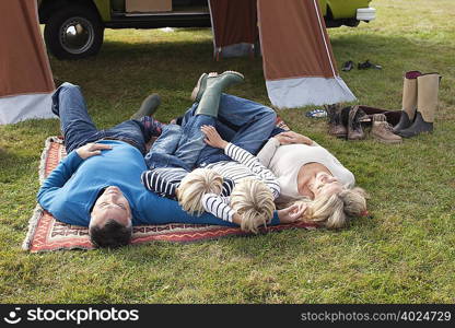 Family lying down in front of tent