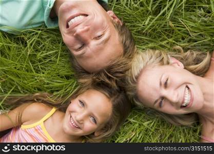 Family lying in grass smiling