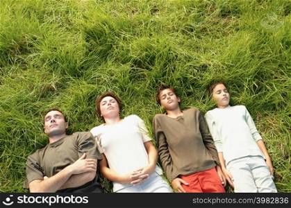 Family lying in row on grass