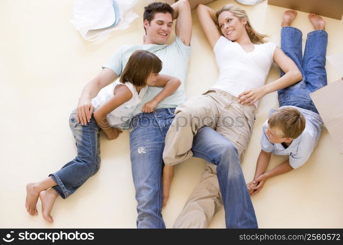 Family lying on floor by open boxes in new home smiling