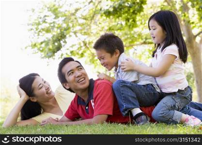 Family lying outdoors being playful and smiling
