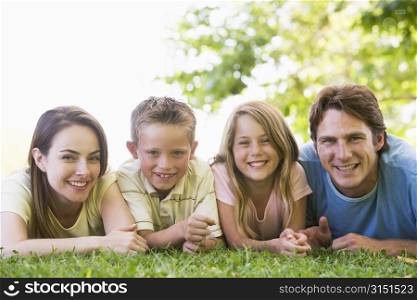 Family lying outdoors smiling