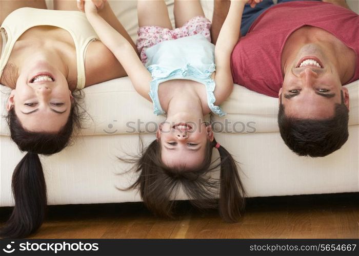 Family Lying Upside Down On Sofa With Daughter