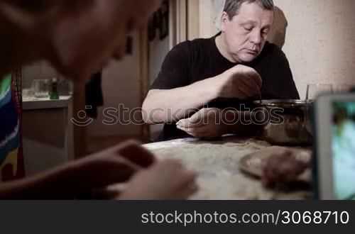 Family making pelmeni: one person giving dough, other man and woman stuffing them and talking