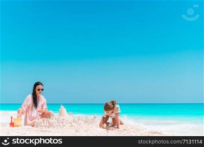 Family making sand castle at tropical white beach. Family making sand castle at tropical white beach. Mother and two girls playing with sand on tropical beach