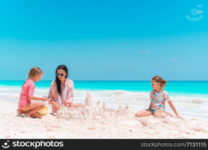 Family making sand castle at tropical white beach. Family making sand castle at tropical white beach. Mother and two girls playing with sand on tropical beach