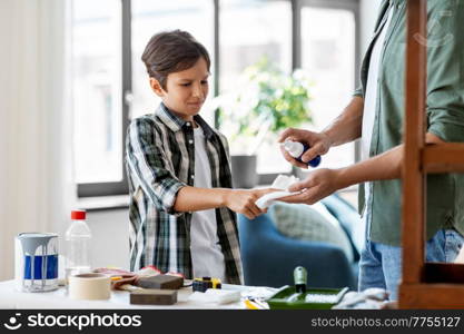 family, medicine and health concept - father healing son&rsquo;s injured finger with antiseptic at home. father treats son&rsquo;s injured finger with antiseptic