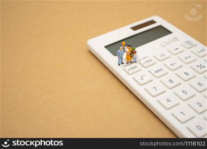 Family Miniature people Pay queue Annual income (TAX) for the year on calculator. using as background business concept and finance concept with copy space for your text or design.