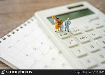 Family Miniature people Pay queue Annual income (TAX) for the year on calculator. using as background business concept and finance concept with copy space for your text or design.