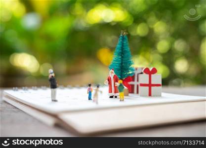 Family Miniature people standing on Christmas tree Celebrate Christmas on December 25 every year. using as background xmas concept with copy spaces for you