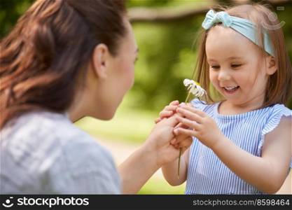 family, motheρod and peop≤concept - happy mother and litt≤daughter with chamomi≤flower at∑mer park or garden. happy mother and daughter with flower at park