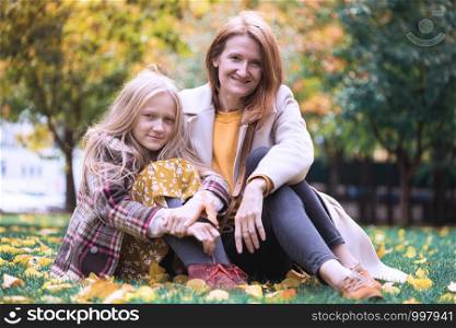 family - mother and daughter in the park holding yellow maple leaves