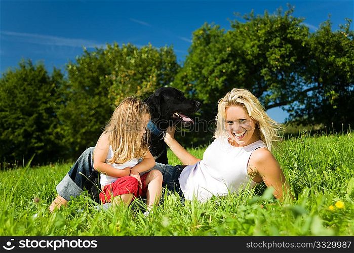 Family (mother and daughter) on a sunlit meadow with their dog