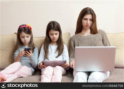 Family (mother and two daughters) watching phone and laptop (gadgets). Family (mother and two daughters) watching phone and laptop (gad