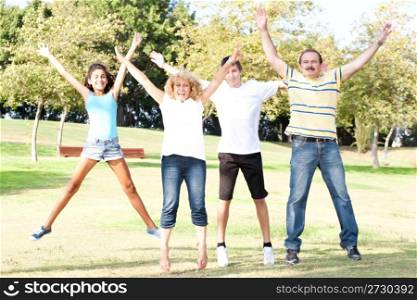 Family - Mother, Father, Children jumping with wide-spread raised arms in park.