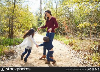 Family mother son and daughter turning circles holding hands at park