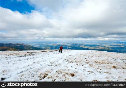 Family (mother with children) walk on autumn mountain plateau with first winter snow