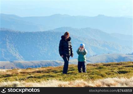 Family (mother with son) walk and make photo on autumn mountain plateau.