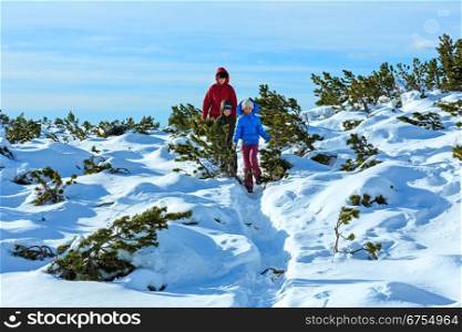 Family (mother with two children) take a walk on winter mountain slope