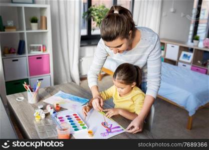 family, motherhood and leisure concept - mother spending time with her little daughter drawing with colors at home. mother with little daughter drawing at home