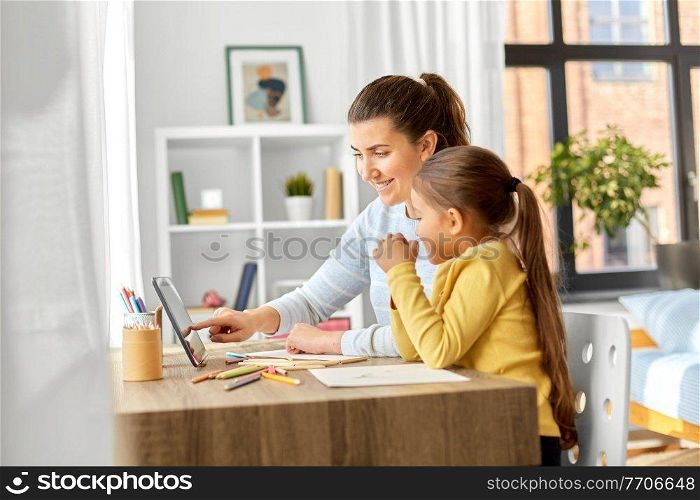 family, motherhood and leisure concept - mother spending time with her little daughter drawing with color pencils and using tablet pc computer at home. mother and daughter with tablet pc drawing at home