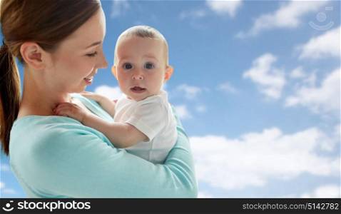family, motherhood and parenthood concept - close up of happy smiling young mother with little baby over blue sky and clouds background. happy young mother with little baby over blue sky