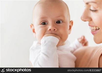 family, motherhood and people concept - close up of happy mother with little baby boy sucking fingers. happy mother with little baby boy sucking fingers