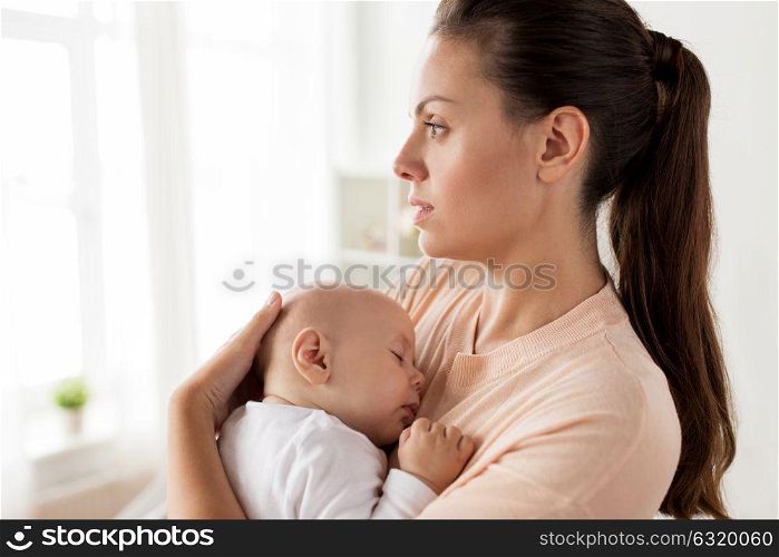 family, motherhood and people concept - close up of mother holding sleeping little baby boy at home. close up of mother holding sleeping baby