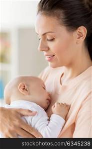 family, motherhood and people concept - close up of mother holding sleeping little baby boy at home. close up of mother holding sleeping baby