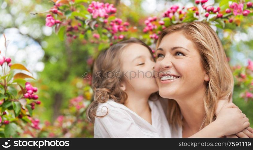 family, motherhood and people concept - happy daughter kissing and hugging smiling mother over cherry blossom background. daughter kissing and hugging happy mother