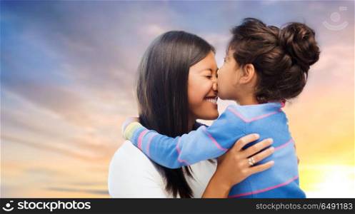 family, motherhood and people concept - happy mother and daughter hugging and kissing over evening sky background. happy mother and daughter hugging and kissing. happy mother and daughter hugging and kissing