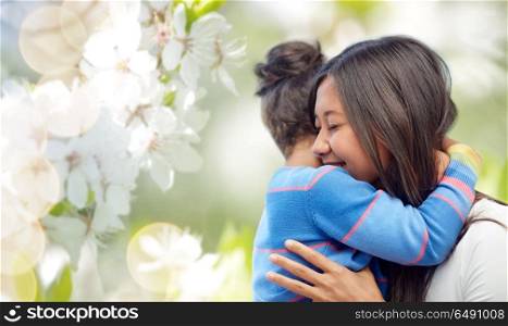family, motherhood and people concept - happy mother and daughter hugging over cherry blossom background. happy mother and daughter hugging. happy mother and daughter hugging