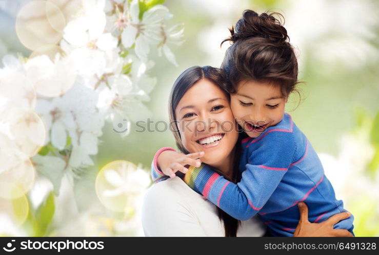 family, motherhood and people concept - happy mother and daughter hugging over cherry blossom background. happy mother and daughter hugging. happy mother and daughter hugging