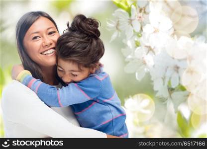 family, motherhood and people concept - happy mother and daughter hugging over cherry blossom background. happy mother and daughter hugging. happy mother and daughter hugging
