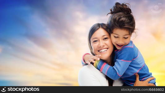 family, motherhood and people concept - happy mother and daughter hugging over evening sky background. happy mother and daughter hugging over evening sky. happy mother and daughter hugging over evening sky