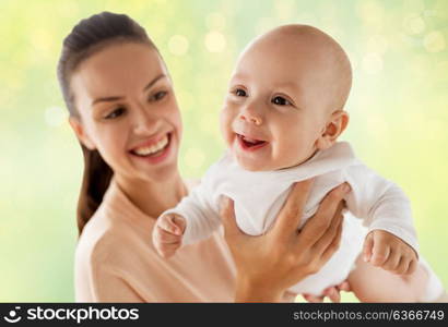 family, motherhood and people concept - happy mother playing with little baby boy over green lights background. happy mother with little baby boy over green