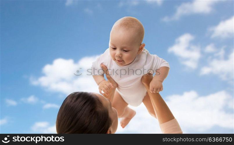 family, motherhood and people concept - happy mother playing with little baby boy over blue sky and clouds background. happy mother playing with little baby boy over sky
