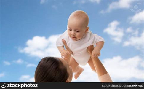 family, motherhood and people concept - happy mother playing with little baby boy over blue sky and clouds background. happy mother playing with little baby boy over sky