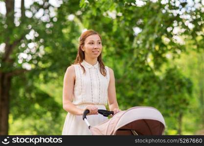 family, motherhood and people concept - happy mother with child sleeping in stroller walking at summer park. happy mother with child in stroller at summer park